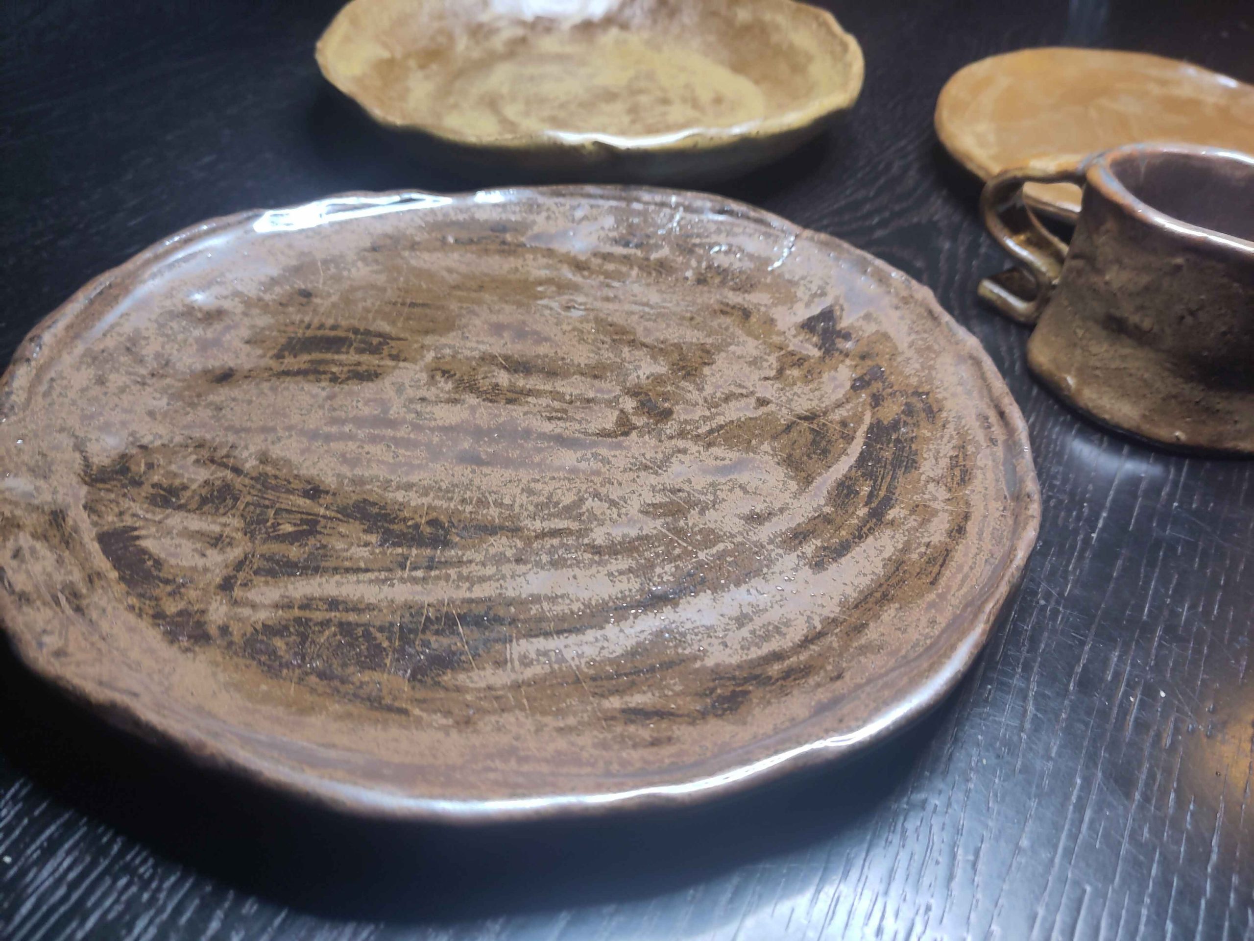 Verschiedene Teller und eine Tasse. selbstgemacht aus Ton mit ungleichmäßiger Glasur