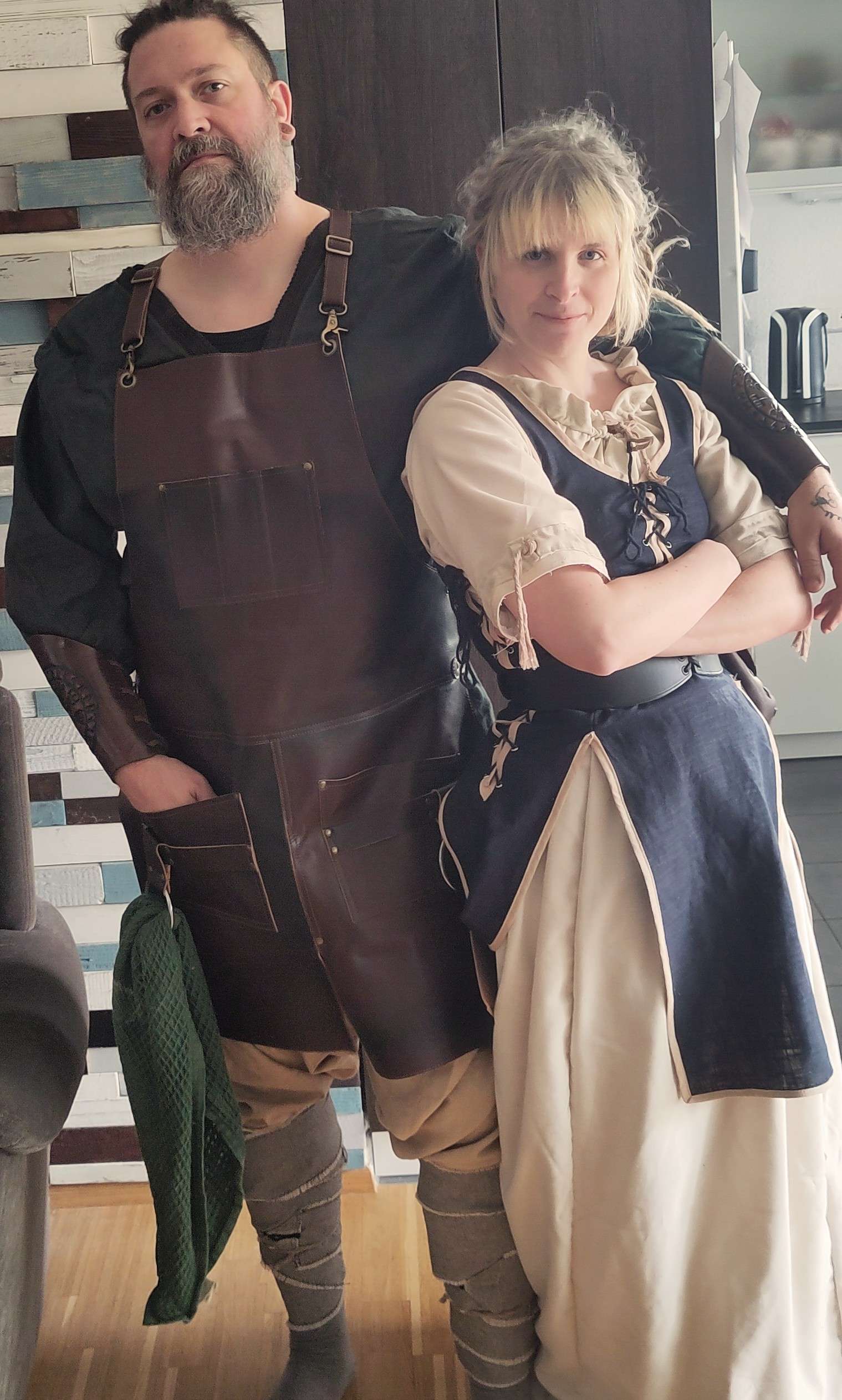 Koch mit Lederschürze und Servicekraft im Kleid